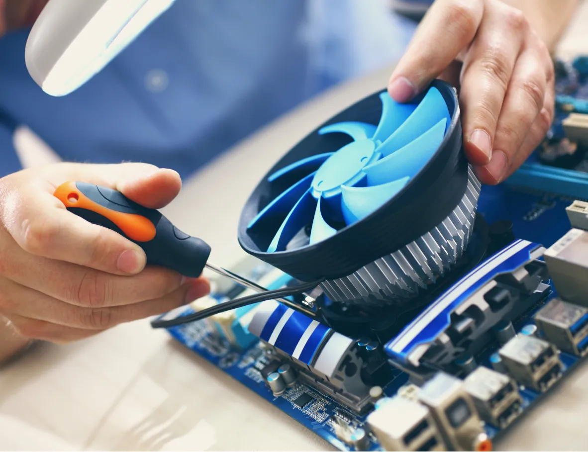 about-2 Hands using a screwdriver to install or fix a CPU cooling fan on a computer motherboard.