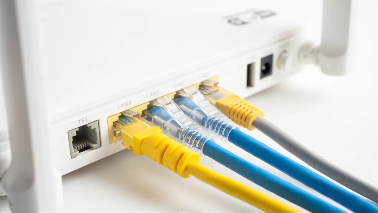 Close-up of a white router with four Ethernet cables plugged into LAN ports and a power cable attached.